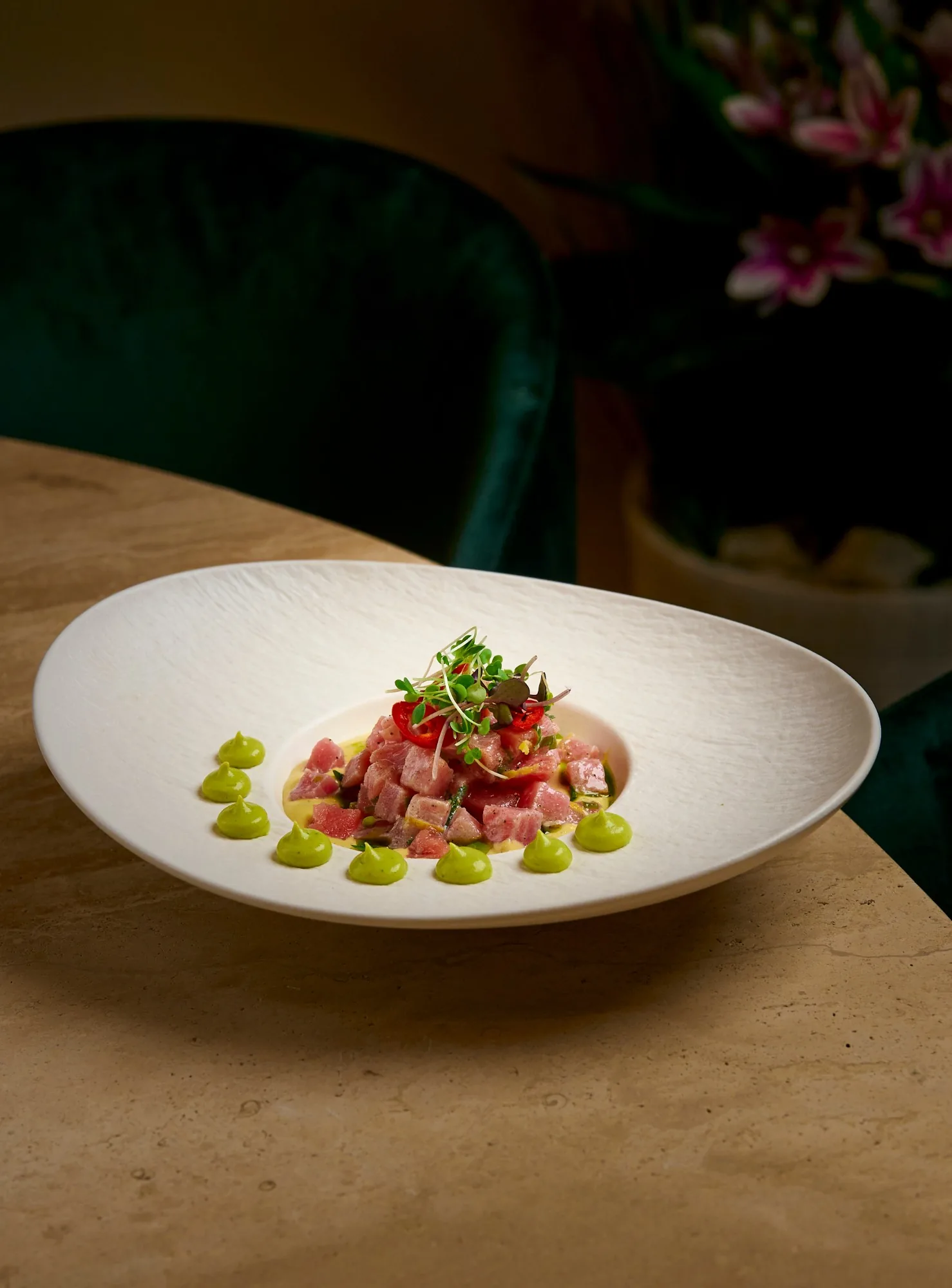 Tuna ceviche with avocado crema on a textured white plate